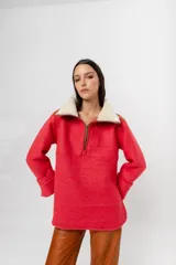 Buzo de lana color beige con cuello alto con cierre y aplique de corderito en el cuello. De mangas rectas y corte amplio.