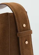 Bolso de mano marrón de piel serraje con asa corta ajustable y asa de hombro. Tiene forro interior, cierre de botón magnético y tamaño mediano.