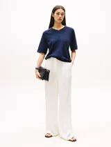 Sweater azul marino de tejido de punto, con cuello en V con ribete de rayas rojas y blancas, mangas cortas y logo bordado en el pecho.