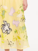 Pollera larga hasta los tobillos, confeccionada en organza color amarillo pálido. Presenta cintura elastizada y flores de tela aplicadas a mano en el delantero.