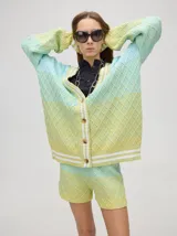 Cardigan tejido de punto con patrón de rombos en degradé de grises y blanco. Tiene corte oversize, mangas largas y cierre frontal con botones.