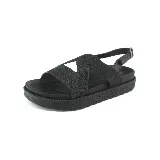 Sandalia negra con plataforma, tiras anchas cruzadas en el empeine y pulsera al tobillo con hebilla.