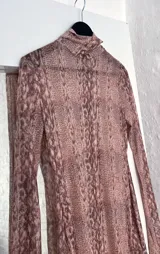 Minivestido de microtul elastizado con estampado animal print en tonos marrones. Diseño ajustado al cuerpo, cuello alto y mangas largas acampanadas.