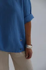 Blusa celeste de lino con cuello redondo y mangas 3/4 con botón.