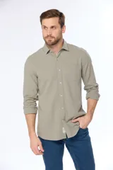 Camisa de lino color beige, de manga larga, con cuello clásico y bolsillo en el pecho.