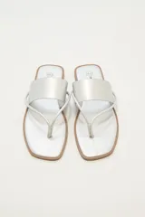 Sandalias plateadas con tira ancha sobre el empeine y tira fina entre los dedos.