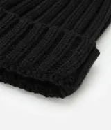 Gorro de lana color blanco con textura acanalada y pompón de pelo sintético en la parte superior.