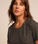 Vestido corto negro con estampado geométrico en color crema, de corte recto, manga corta y cuello redondo. Incluye cinturón fino del mismo tejido.
