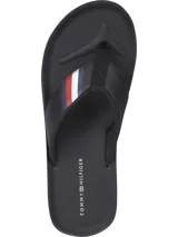 Ojotas negras Tommy Hilfiger con tira ancha de poliuretano acolchada y suela de goma EVA. Detalle de cinta distintiva con los colores de la marca en la tira.
