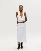 Conjunto de top halter blanco con escote en V cruzado y falda midi blanca con corte irregular.