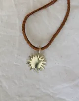Gargantilla con dije de sol realizado en bronce y tira de cuero marrón.