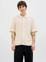 Polo de hombre color crema, tejido de punto cable, con cuello tipo polo, manga corta y cierre con botones.