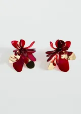 Par de aros colgantes con forma de flor, de tamaño mediano, con pétalos de acrílico rojo y detalles metálicos dorados.