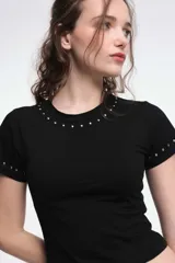 Remera blanca de algodón con cuello redondo y mangas cortas, con detalle de tachas plateadas en cuello y mangas.