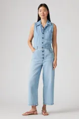Mono de jean celeste claro, sin mangas, con cuello camisero, cierre frontal con botones y bolsillos laterales.