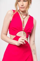 Vestido corto fucsia con escote en V y corte a la cintura. Presenta aberturas laterales y lazo ajustable en la espalda.