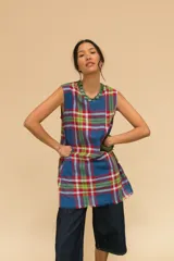 Vestido corto sin mangas con estampado de cuadros en tonos azul, rojo, verde y blanco. Tiene cuello redondo y ruedo con flecos.