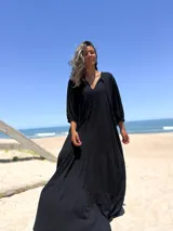 Vestido largo negro con escote en V y mangas 3/4 amplias.