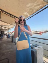 Bandolera pequeña color negro, de material símil cuero, con correa fina y herrajes plateados.