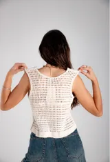 Chaleco sin mangas de tela blanca con bordados florales en hilo azul y blanco, con cierre frontal de botones.