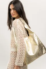 Bolso tipo shopper dorado de cuero natural, sin forro, con base plana y doble asa de hombro.