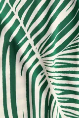 Vestido túnica a la rodilla en tejido liviano de viscosa con cuello mao y abertura en V. Modelo de corte holgado con hombros levemente caídos, mangas cortas y bajo recto con tajos laterales. Parte posterior algo más larga. Sin forrar. Estampado con hojas de palmera en verde y blanco.