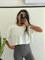 Remera corta de algodón blanca, con cuello redondo y manga corta holgada. Presenta un pequeño logo bordado en el pecho.