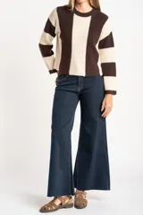 Sweater de tejido de punto grueso, con diseño de rayas verticales anchas en tonos marrón oscuro y negro. Presenta cuello redondo y mangas largas.