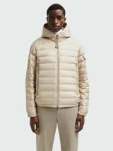 Campera puffer color crema con capucha, cierre frontal con cremallera, bolsillos laterales con cremallera y logo en la manga.