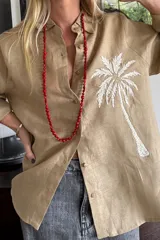 Camisa blanca de lino con bordado de una palmera en el pecho.