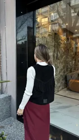 Chaleco negro de cuero descarne con terminación en picos y tachas metálicas.