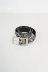 Cinto con estampado animal print en blanco y negro, con hebilla metálica plateada de forma rectangular.