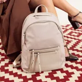 Mochila negra de tela impermeable con detalles en cuero sintético. Tiene un compartimento principal con cierre, un bolsillo frontal con cierre y un compartimento interno para notebook de 15 pulgadas.