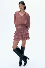 Blusa rosa con estampado floral, cuello con volados y escote en V con tiras finas para atar. Modelo de manga larga con hombros caídos y fruncido elástico con ribete de volados en puños y bajo.