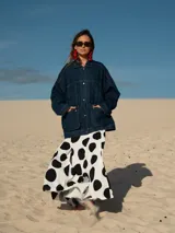 Campera de jean azul oscuro, de corte oversize, con cuello clásico, cierre frontal con botones metálicos, bolsillos con solapa en el pecho y estampado de lunares grandes en blanco y negro en la espalda.