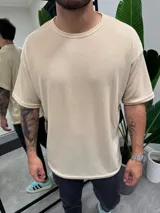 Remera color beige de punto símil tejido, corte holgado y mangas cortas.