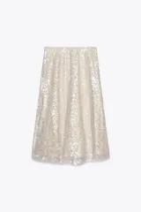 Falda midi color crema con lentejuelas plateadas, de tiro alto y corte evasé.