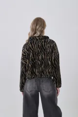 Campera corta de tejido peluche (corderito) con cierre frontal y cuello camisero. Presenta un estampado animal print de cebra o tigre en tonos marrón claro y negro.