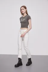 Remera gris de corte crop con cuello redondo y mangas cortas. Estampado frontal con alas y texto "Angel on Earth".