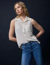 Blusa color crema sin mangas, con cuello camisero, cierre frontal con botones y bolsillo de crochet.