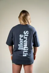Remera gris con estampado en el frente con la frase "Fear Less". En la espalda tiene un estampado vertical con la frase "More Strength".