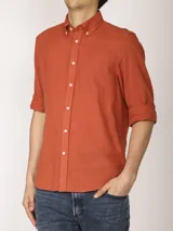 Camisa azul marino de lino y algodón, con cuello abotonado, manga larga con puños enrollados, bolsillo de parche en el pecho y cierre frontal con botones.