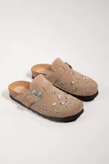 Suecos de cuero gamuzado color marrón chocolate, con apliques de tachas plateadas y hebilla decorativa metálica.