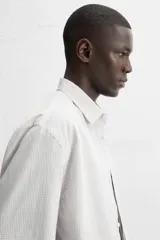 Camisa de hombre relaxed fit confeccionada en tejido de algodón a cuadros. Tiene cuello solapa, manga larga con puños abotonados, bolsillo en el pecho y cierre frontal con botones.