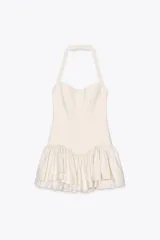 Minivestido blanco con cuello halter, escote recto y falda con volantes y forro tipo short. Presenta cierre con botones en el cuello y cremallera oculta en la espalda.