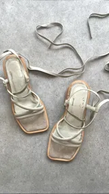 Sandalias plateadas con tiras finas cruzadas y tobilleras con cordones. Tacón de madera.