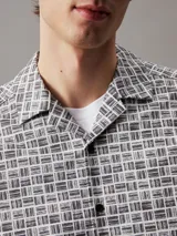 Camisa de manga corta con cuello cubano y corte boxy. Diseño con estampado de rejilla en blanco y negro y logo de Calvin Klein estampado.