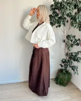 Campera de jean blanca de corte cropped, con cuello camisero, mangas largas con puños abotonados, cierre frontal con botones metálicos y bolsillos de parche en el pecho.