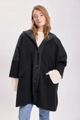 Abrigo negro de paño con corte amplio, cuello camisero, cierre frontal con botones y mangas tres cuartos. Tiene bolsillos laterales y detalle de canesú en la espalda.