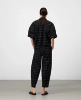 Pantalón de mujer color negro con estampado de cuadros blancos, corte barrel fit, cintura elástica en la espalda, bolsillos laterales y bolsillos de vivo con solapa en la espalda.